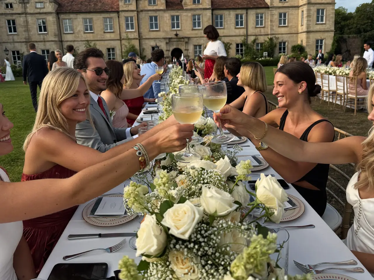 Guests clinking champagne glasses across the marquee table