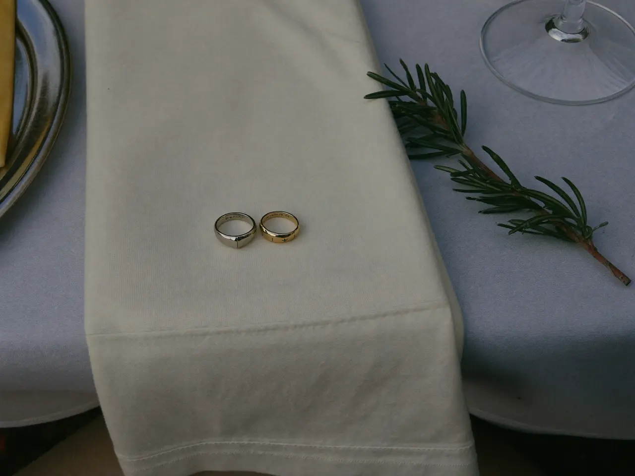 The rings on an ivory napkin with a sprig of rosemary