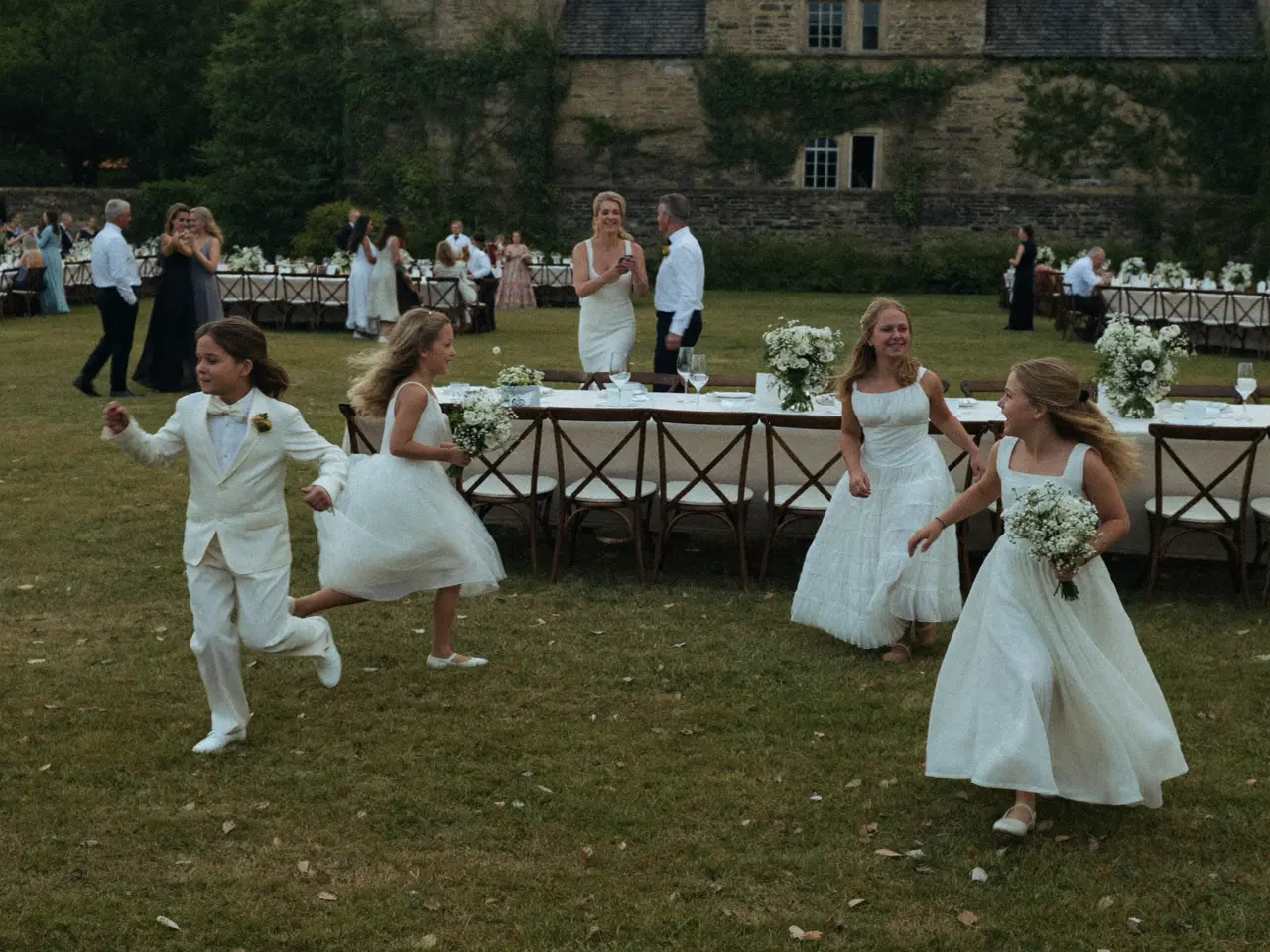 Children chasing each other across the lawn between the tables