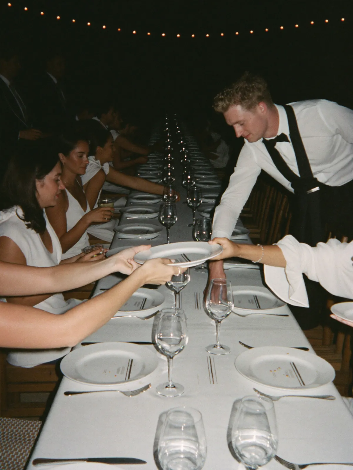 Waiters setting plates down both sides of the long table at the same moment