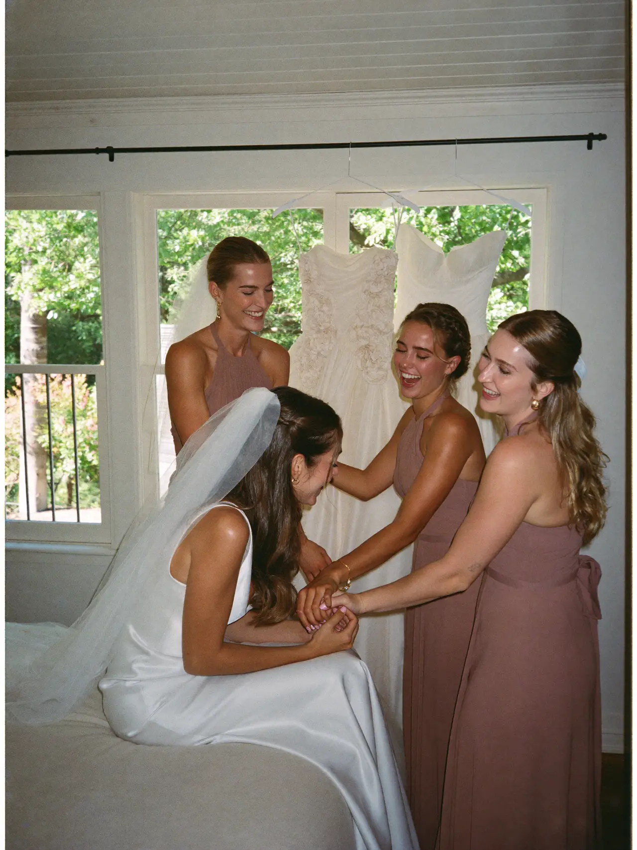 The bride and her bridesmaids laughing while getting ready in the morning