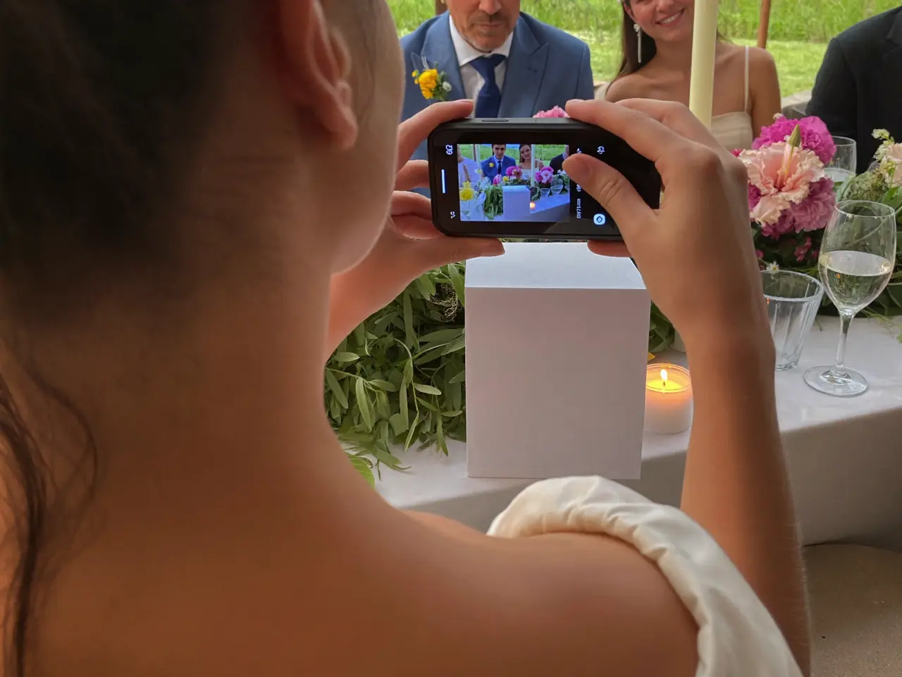 Wedding guest photographing the top table on her phone during the reception