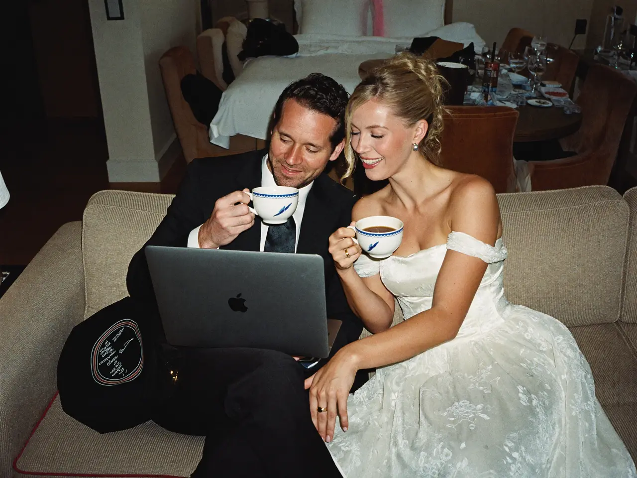 The couple with tea, browsing the finished album on a laptop
