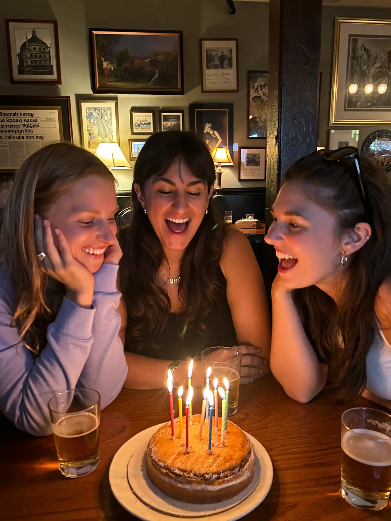 Friends singing around a birthday cake in a pub